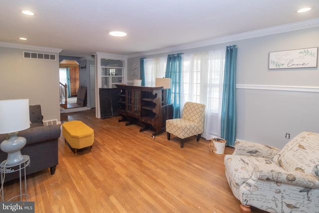 sitting room with visible vents, wood finished floors, and ornamental molding