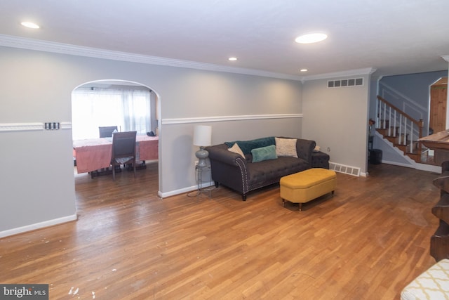 living room with arched walkways, light wood-style flooring, and visible vents