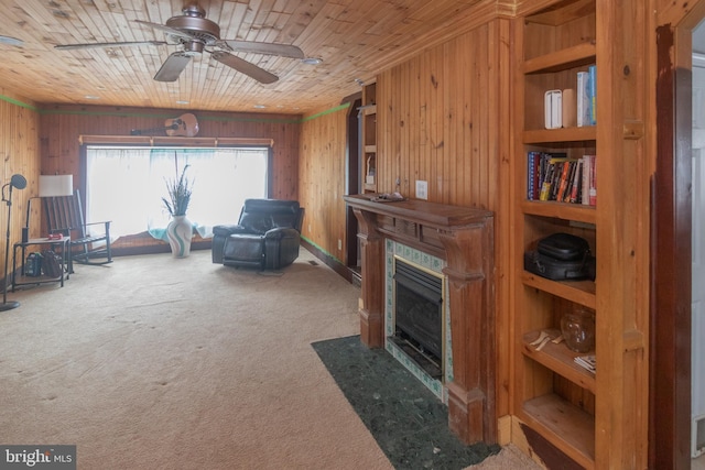 living area featuring carpet, a fireplace with flush hearth, ceiling fan, wooden walls, and wooden ceiling