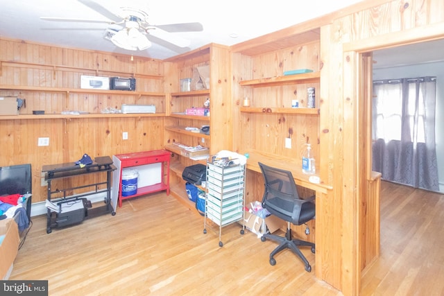 home office featuring ceiling fan, wood finished floors, and wooden walls