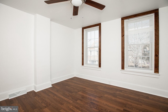 unfurnished room featuring ceiling fan, dark wood-style flooring, visible vents, and baseboards