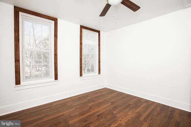 spare room with ceiling fan, baseboards, and dark wood-style flooring