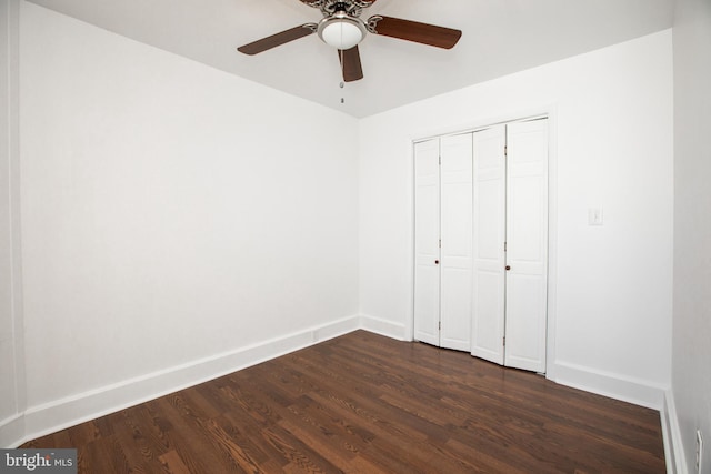 unfurnished bedroom featuring dark wood-style flooring, a closet, a ceiling fan, and baseboards