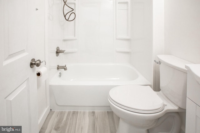 bathroom featuring washtub / shower combination, toilet, and wood finished floors