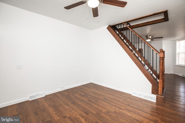 empty room with stairway, wood finished floors, visible vents, and baseboards