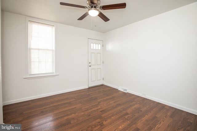 unfurnished room with ceiling fan, dark wood finished floors, visible vents, and baseboards