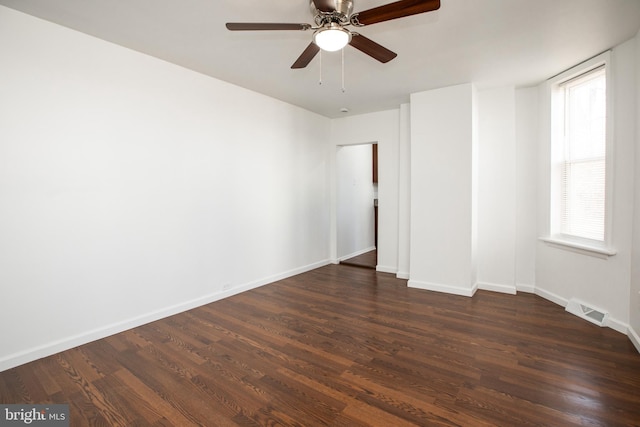 empty room with a ceiling fan, baseboards, visible vents, and dark wood-style flooring