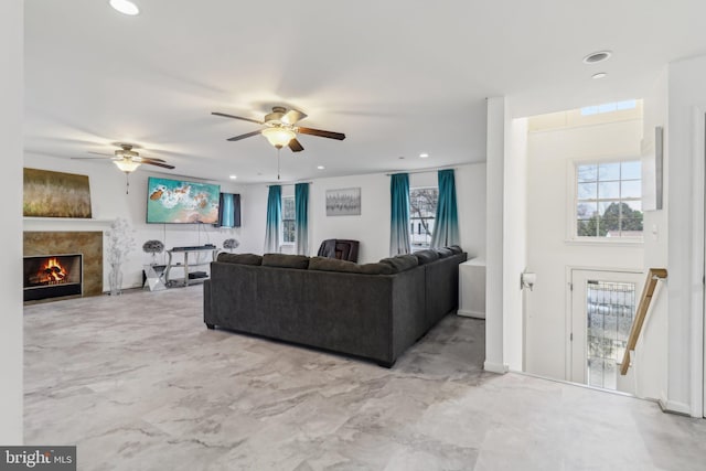 living room with a ceiling fan, recessed lighting, a warm lit fireplace, and marble finish floor