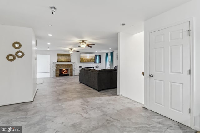 unfurnished living room featuring a warm lit fireplace, ceiling fan, and recessed lighting