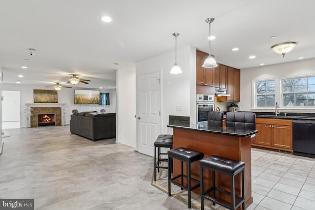 kitchen featuring a sink, stainless steel oven, a kitchen breakfast bar, black dishwasher, and a lit fireplace