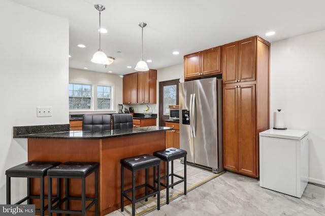 kitchen with appliances with stainless steel finishes, brown cabinets, a peninsula, and a kitchen breakfast bar