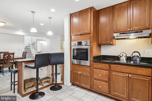 kitchen with brown cabinetry, oven, under cabinet range hood, and black electric stovetop