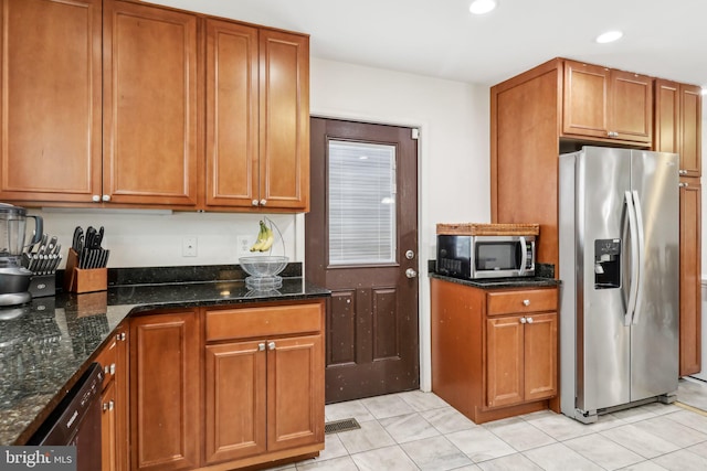 kitchen featuring light tile patterned floors, recessed lighting, stainless steel appliances, dark stone counters, and brown cabinetry