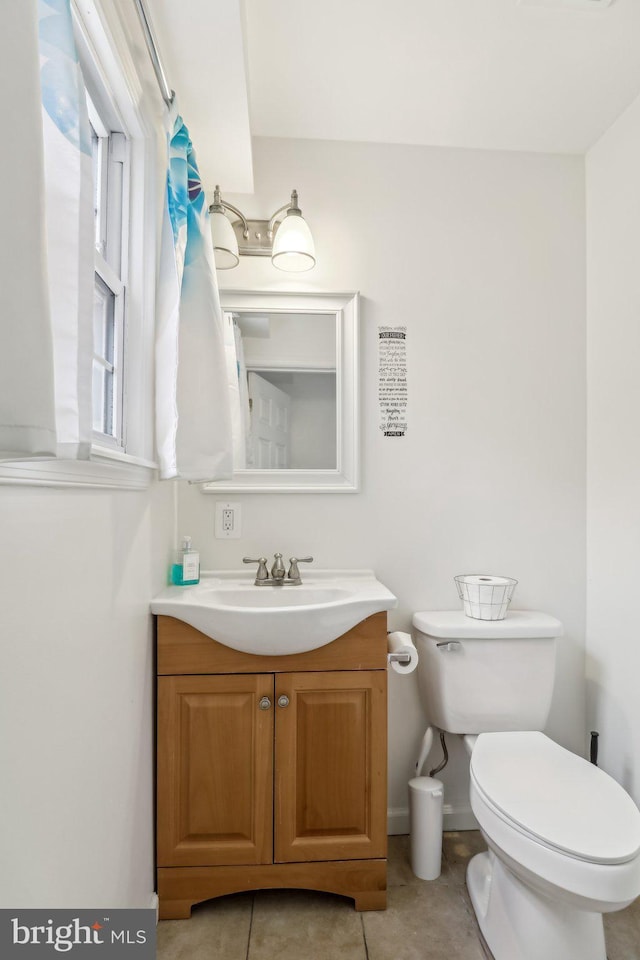 half bath with toilet, tile patterned floors, and vanity