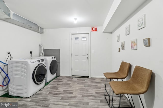 laundry room with laundry area, baseboards, separate washer and dryer, and wood finished floors