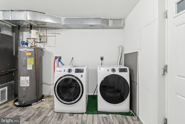 clothes washing area with water heater, laundry area, wood finished floors, and washer and dryer