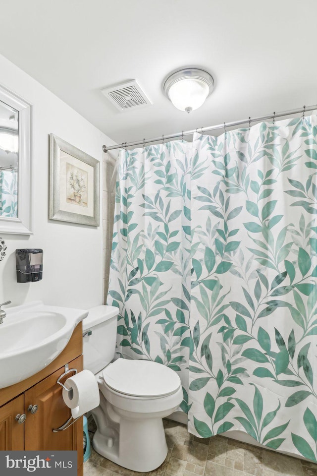 bathroom featuring visible vents, a shower with shower curtain, toilet, stone finish flooring, and vanity