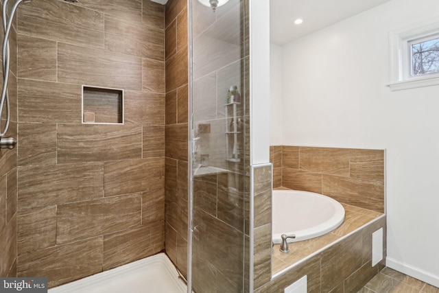 full bathroom featuring a garden tub, a shower stall, and baseboards