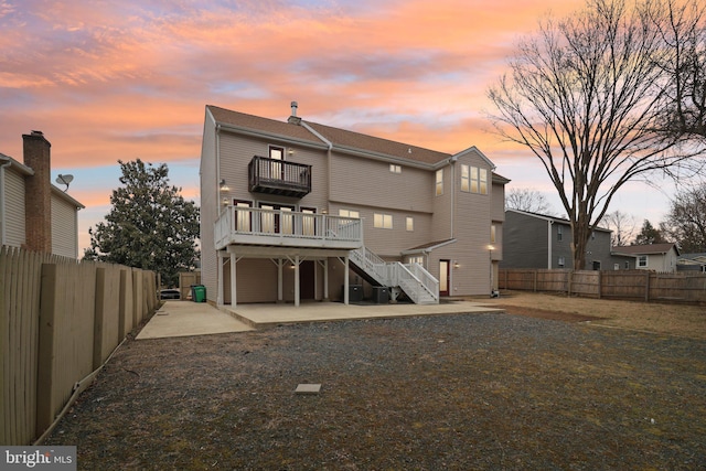 rear view of house with a patio area, a fenced backyard, a balcony, and stairs