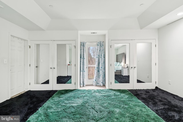 bedroom with french doors, dark carpet, visible vents, and multiple closets