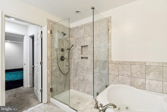 bathroom with a shower stall, a tub with jets, and tile patterned floors