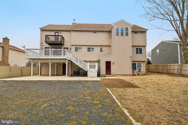 back of property featuring a fenced backyard, stairs, a lawn, a wooden deck, and a patio area