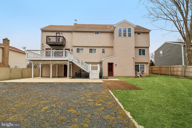 rear view of house with a fenced backyard, a yard, stairway, a wooden deck, and a patio area