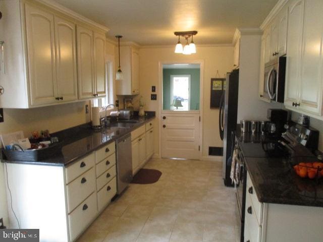 kitchen with stainless steel appliances, dark countertops, and ornamental molding