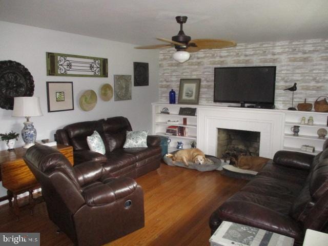 living room with a ceiling fan, a fireplace, and wood finished floors