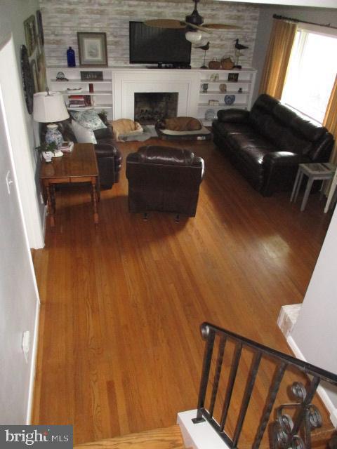 living area with a fireplace, wood finished floors, and a ceiling fan