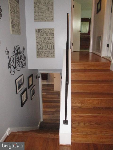 stairway with wood finished floors, visible vents, and baseboards