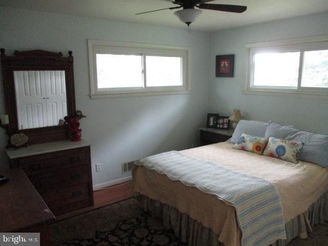 bedroom with a ceiling fan, multiple windows, and visible vents