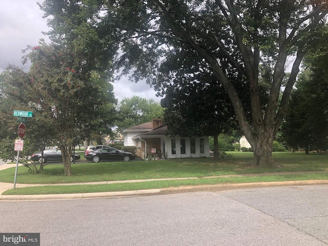 view of property hidden behind natural elements with a front lawn