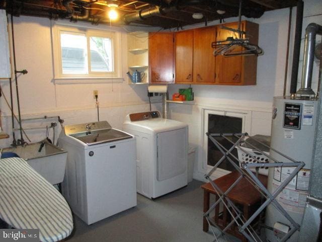 washroom featuring water heater, washer and clothes dryer, and a sink