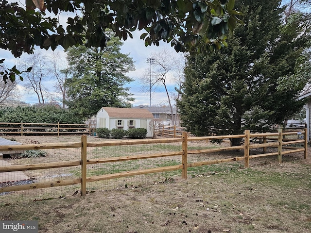 view of yard with a rural view, fence, and an outbuilding