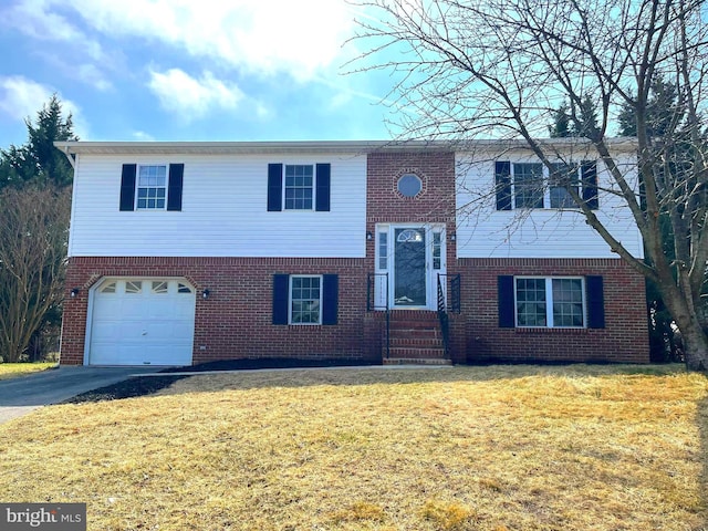 bi-level home featuring driveway, brick siding, an attached garage, and a front yard