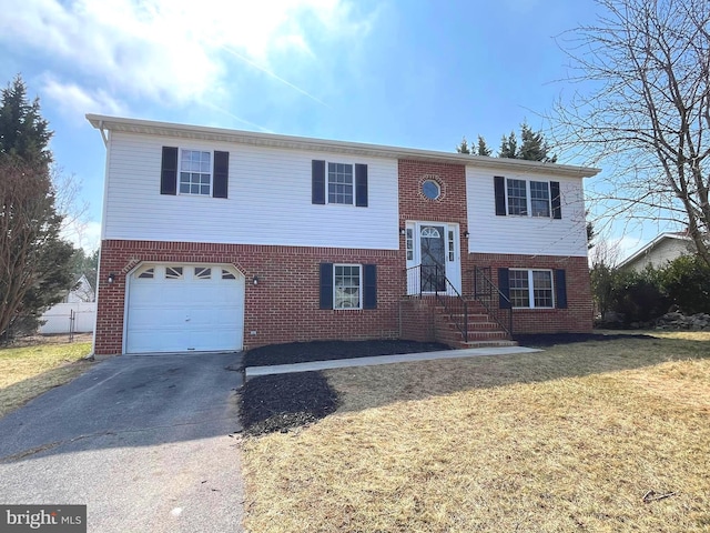 bi-level home with aphalt driveway, an attached garage, brick siding, and a front lawn