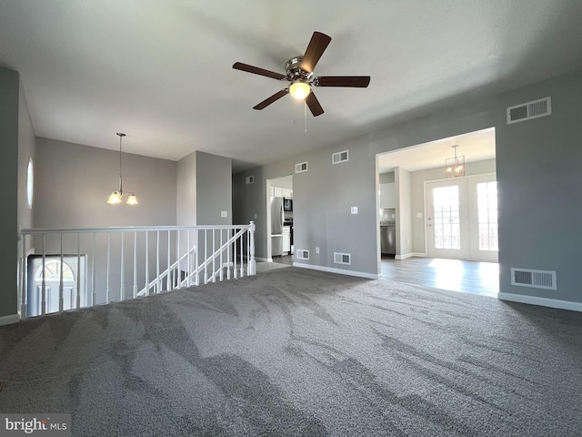 carpeted spare room featuring ceiling fan with notable chandelier and visible vents