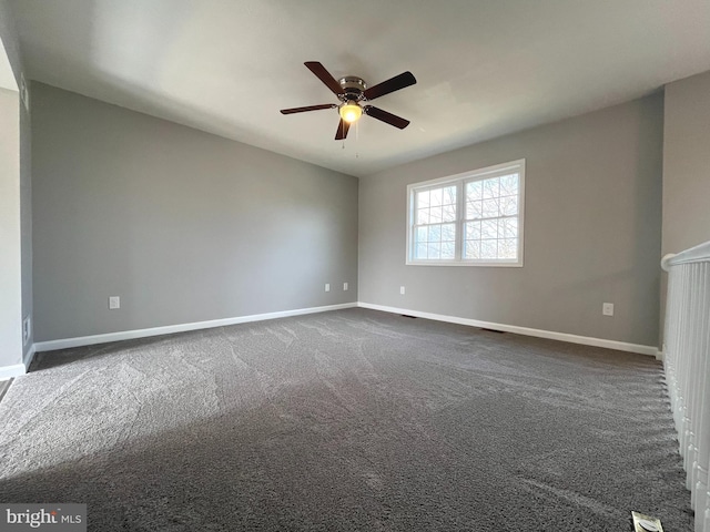 unfurnished room with a ceiling fan, baseboards, and dark carpet