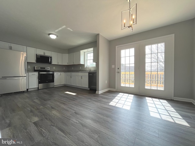 kitchen with a sink, appliances with stainless steel finishes, dark wood-style flooring, and white cabinetry