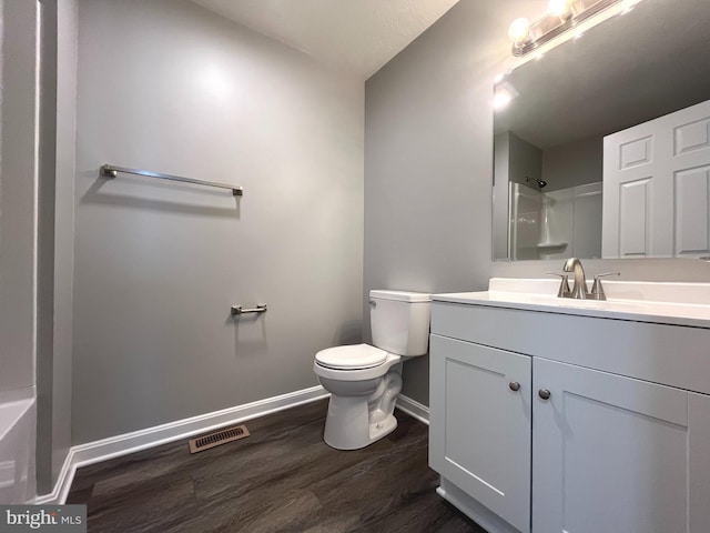 bathroom featuring vanity, wood finished floors, visible vents, walk in shower, and toilet