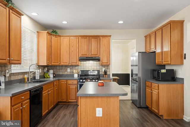 kitchen featuring dark wood finished floors, a sink, black appliances, under cabinet range hood, and a center island