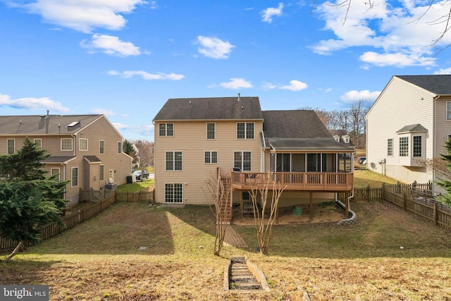 back of house with stairway, a sunroom, a lawn, a deck, and a fenced backyard