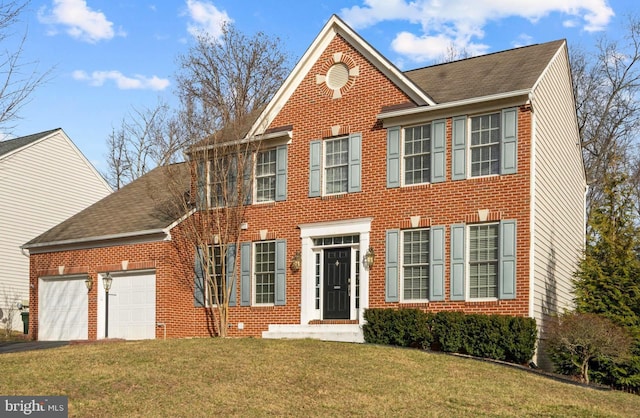 colonial inspired home with a garage, brick siding, a front lawn, and aphalt driveway