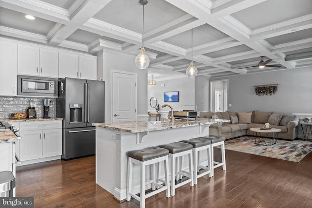 kitchen featuring dark wood finished floors, decorative backsplash, appliances with stainless steel finishes, light stone countertops, and white cabinetry