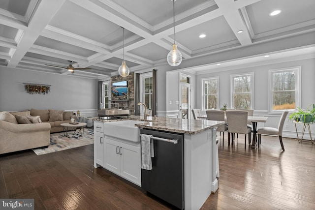 kitchen with light stone counters, dark wood-style floors, hanging light fixtures, a sink, and dishwashing machine