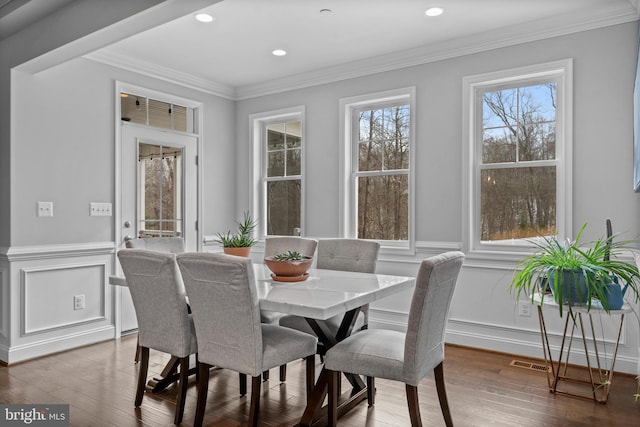 dining space with wainscoting, visible vents, wood finished floors, and ornamental molding