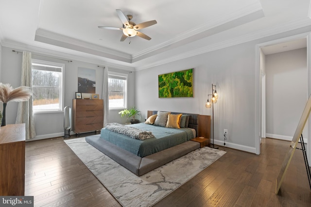 bedroom with wood-type flooring, a tray ceiling, and baseboards