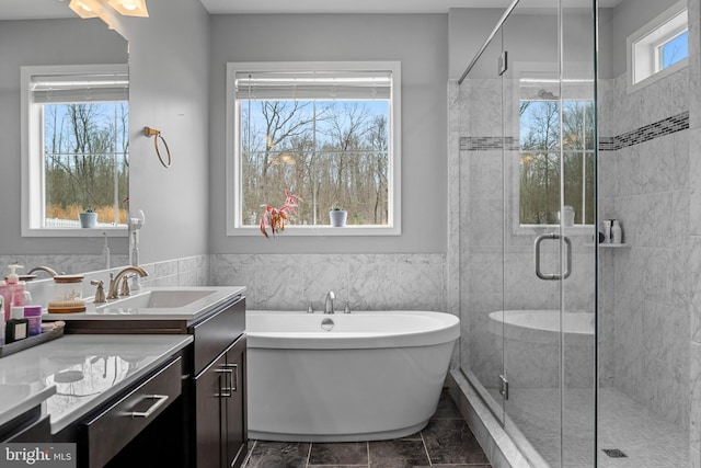 full bathroom with a stall shower, a wainscoted wall, a soaking tub, and vanity