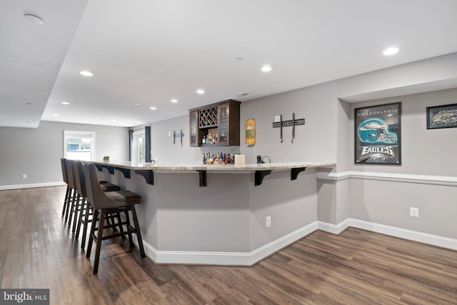 kitchen featuring dark wood-style floors, recessed lighting, a kitchen bar, and baseboards